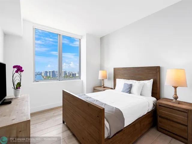 a bedroom with a bed and a flat tv screen on dresser
