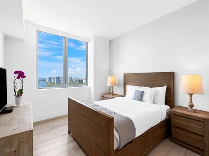 a bedroom with a bed and a flat tv screen on dresser
