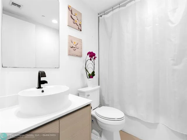 a bathroom with a sink a toilet and shower curtain