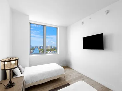 a bedroom with a bed tv and a window