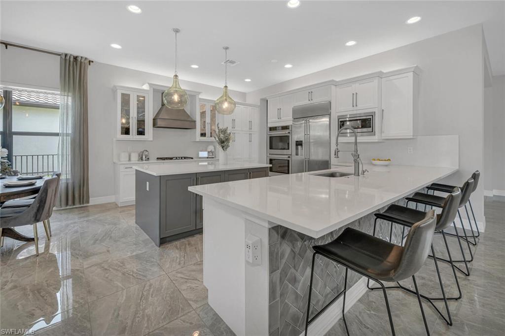 4541 Azalea Drive Naples, FL 34119 - Photo 7 of 35 Kitchen with built in appliances, decorative light fixtures, custom range hood, and white cabinets