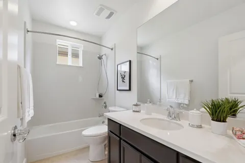 a bathroom with a granite countertop sink toilet a large mirror a shower and a tub