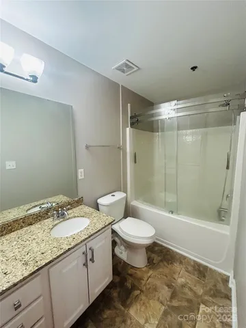 a bathroom with a granite countertop sink a toilet a mirror and shower