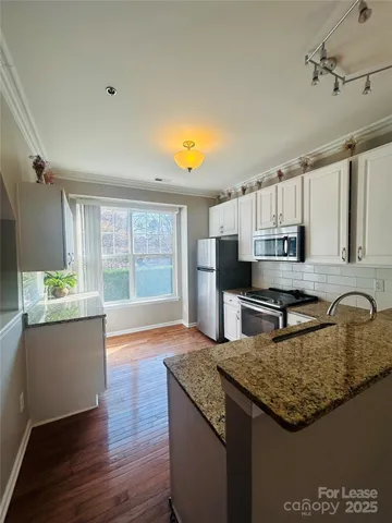 a kitchen with granite countertop a stove a sink and a refrigerator