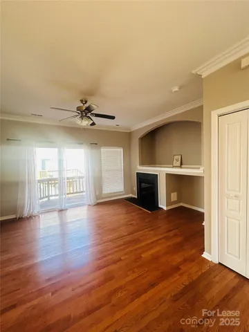 an empty room with wooden floor fireplace and windows