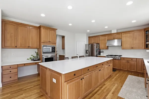 a large kitchen with stainless steel appliances granite countertop a large counter top a sink a stove and a refrigerator