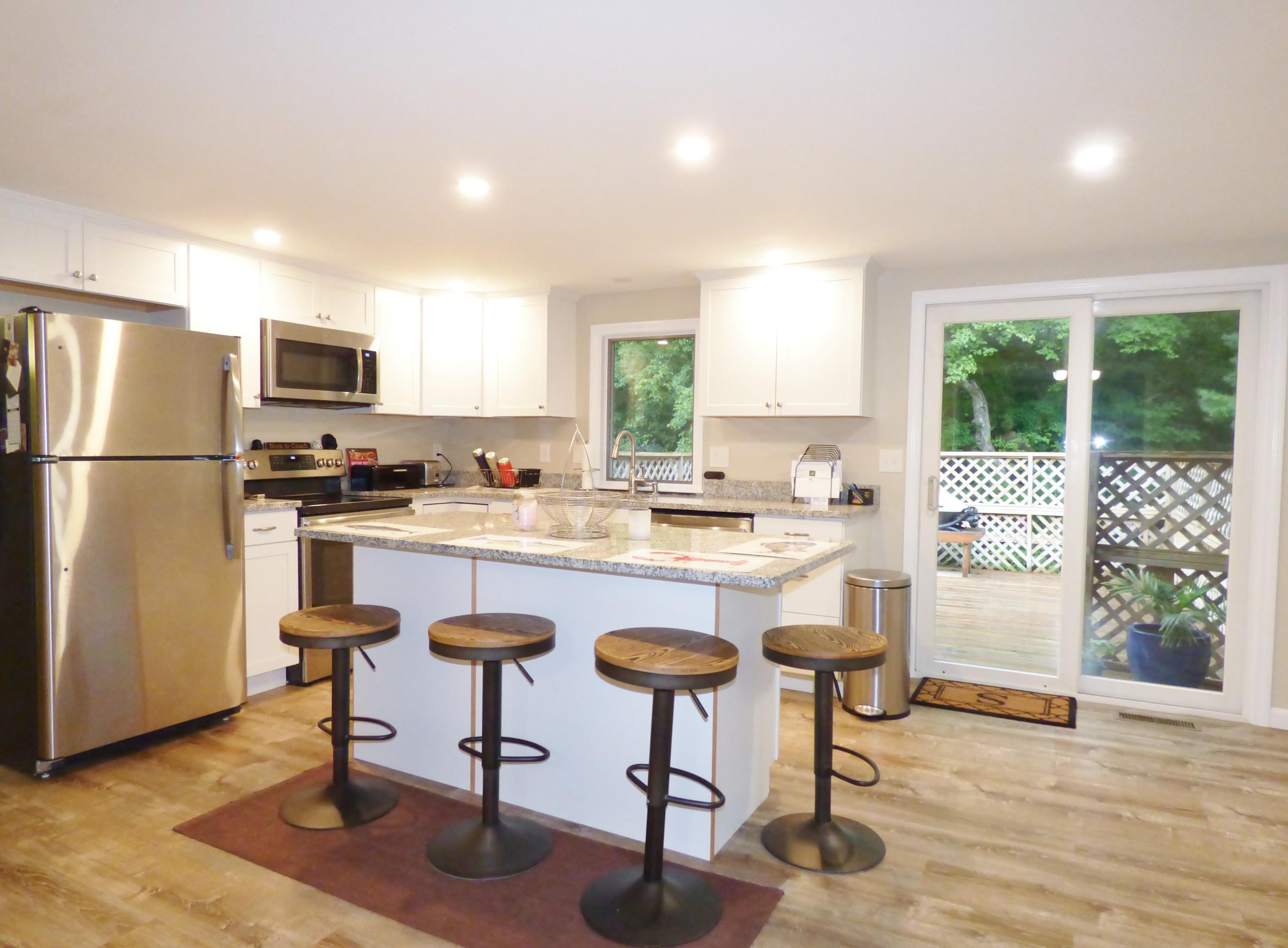 100 Taramac Road Centerville, MA 02632 - Photo 3 of 18 a kitchen with kitchen island a refrigerator a stove a dining table and chairs with wooden floor