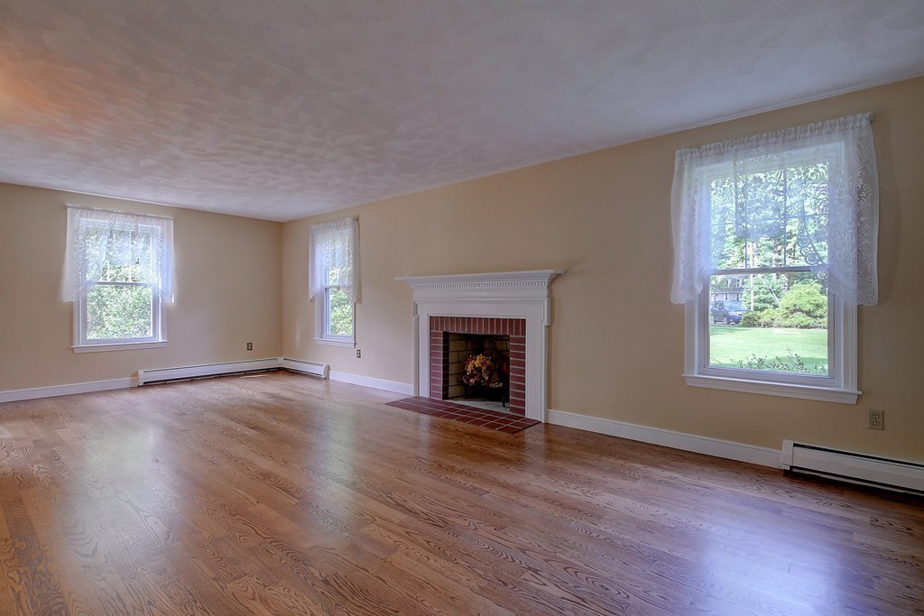 32 Bayberry Road Groton, MA 01450 - Photo 3 of 30 an empty room with wooden floor fireplace and windows