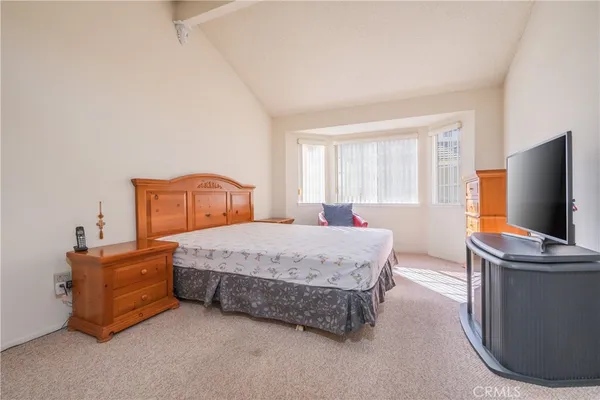 a bedroom with a bed and flat tv screen on the dresser