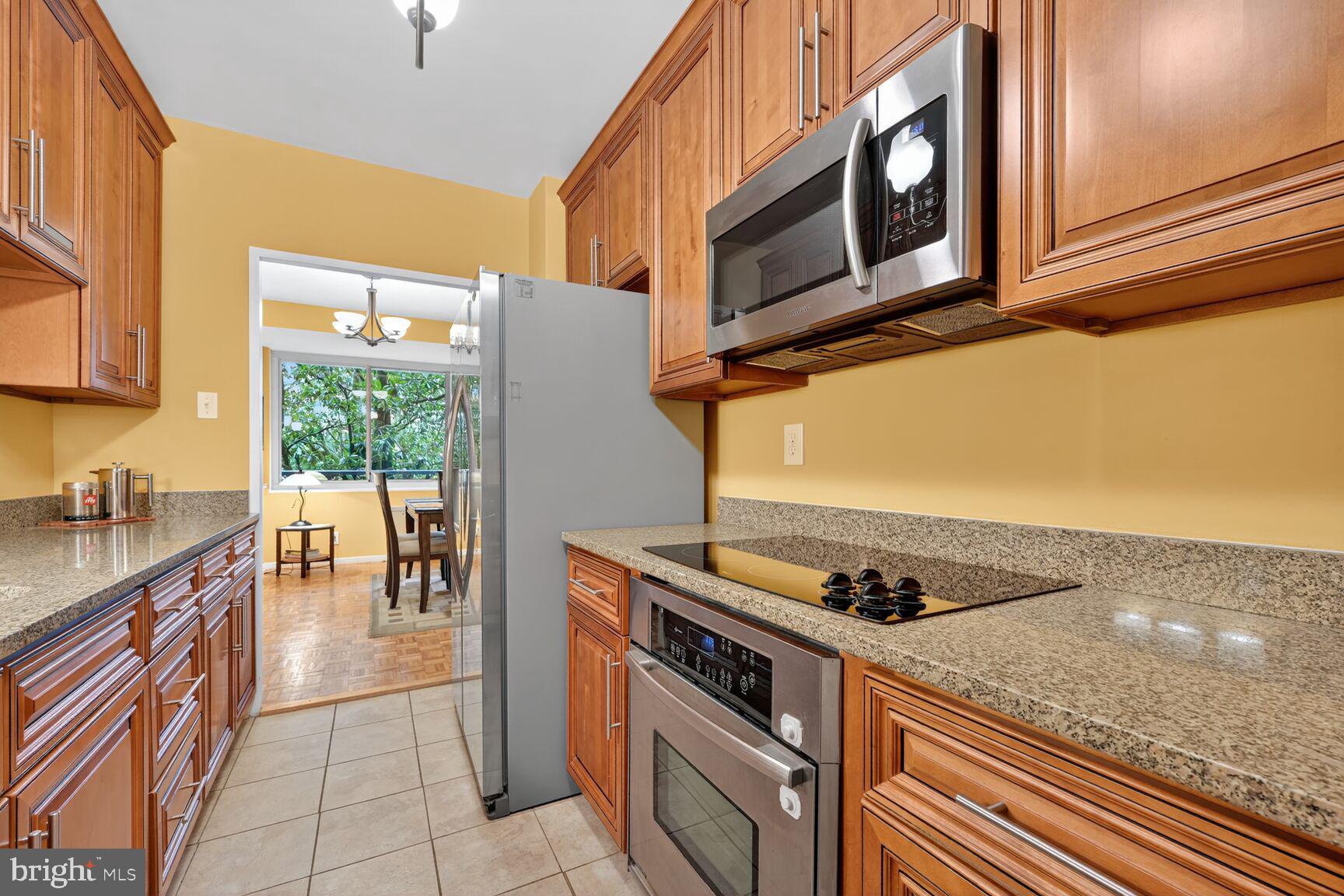 3900 Watson Place Northwest, Unit B1G Washington, DC 20016 - Photo 6 of 16 a kitchen with stainless steel appliances granite countertop a stove a sink and a microwave