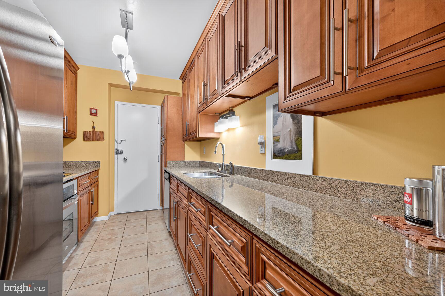 3900 Watson Place Northwest, Unit B1G Washington, DC 20016 - Photo 7 of 16 a kitchen with stainless steel appliances granite countertop a sink and cabinets