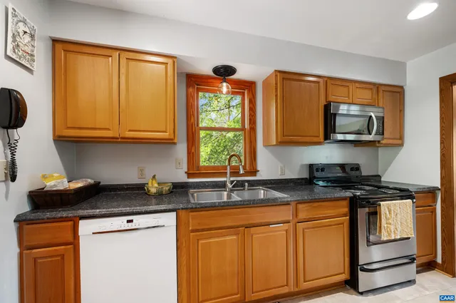 a kitchen with stainless steel appliances granite countertop a stove a sink a microwave and wooden cabinets