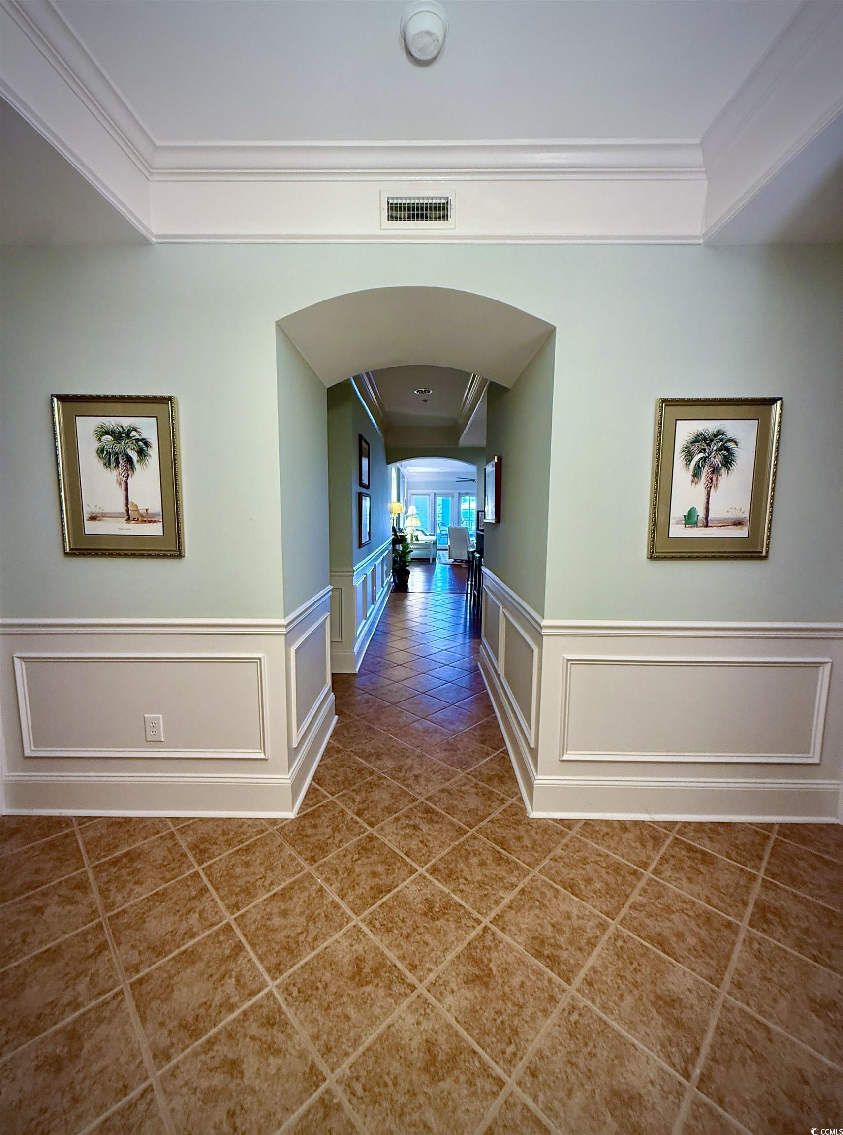 1330 Villa Marbella Court, Unit 303 Myrtle Beach, SC 29572 - Photo 31 of 40 Corridor featuring arched walkways, tile patterned floors, crown molding, wainscoting, and a decorative wall