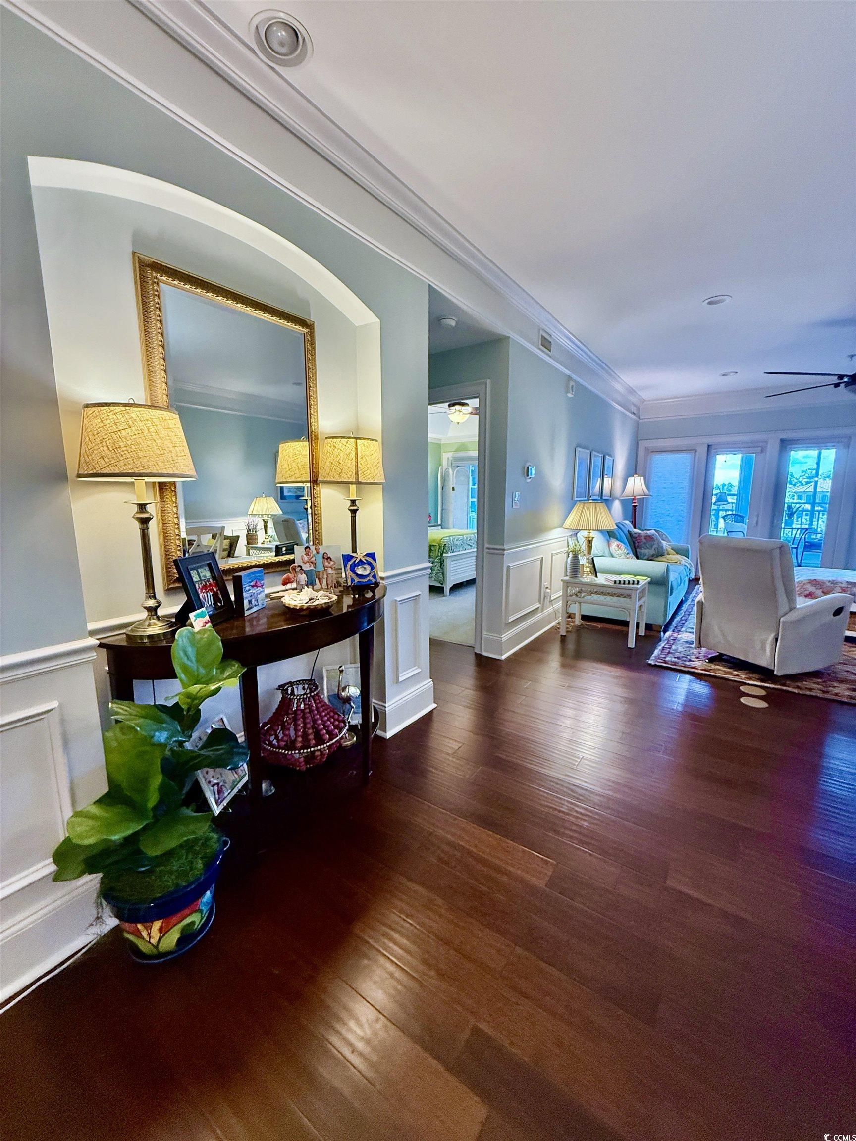 1330 Villa Marbella Court, Unit 303 Myrtle Beach, SC 29572 - Photo 7 of 40 Corridor featuring a wainscoted wall, a decorative wall, wood finished floors, and ornamental molding