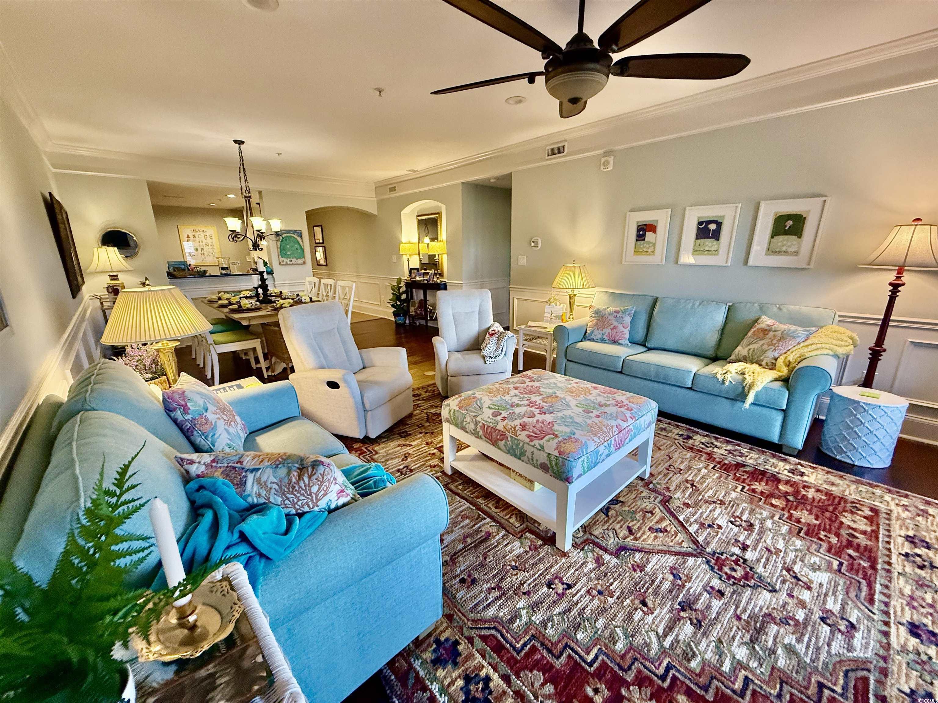 1330 Villa Marbella Court, Unit 303 Myrtle Beach, SC 29572 - Photo 8 of 40 Living area featuring crown molding, arched walkways, ceiling fan, a chandelier, and a decorative wall