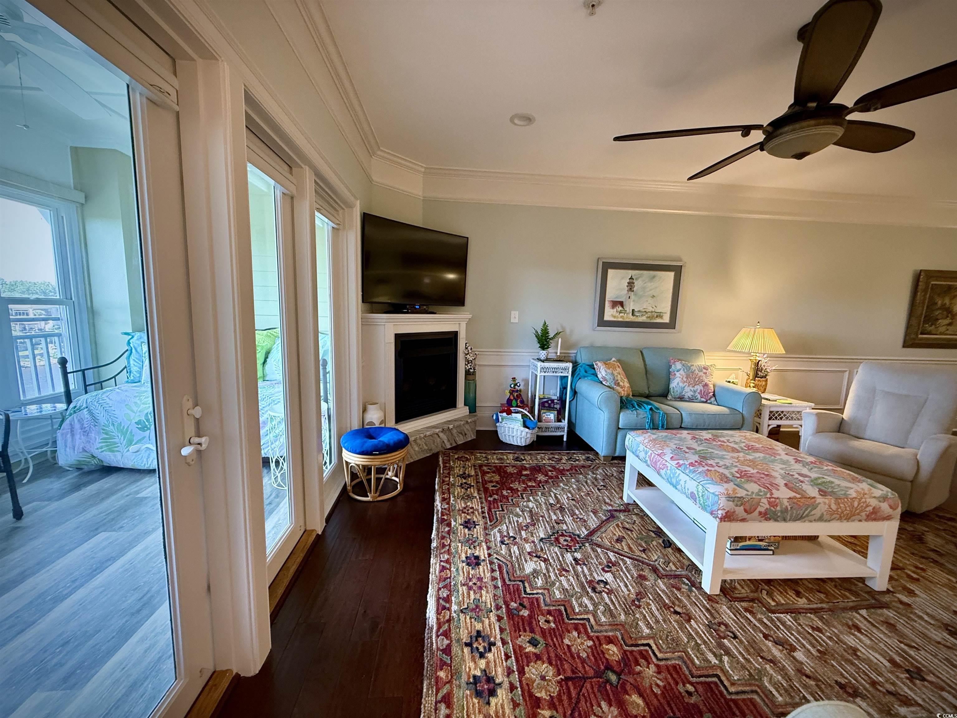 1330 Villa Marbella Court, Unit 303 Myrtle Beach, SC 29572 - Photo 9 of 40 Living area with ornamental molding, ceiling fan, wood finished floors, wainscoting, and a fireplace with raised hearth