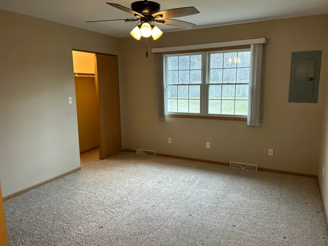 an empty room with a chandelier fan and windows