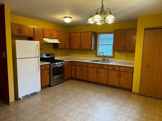 a kitchen with stainless steel appliances a sink a stove a refrigerator cabinets and a window