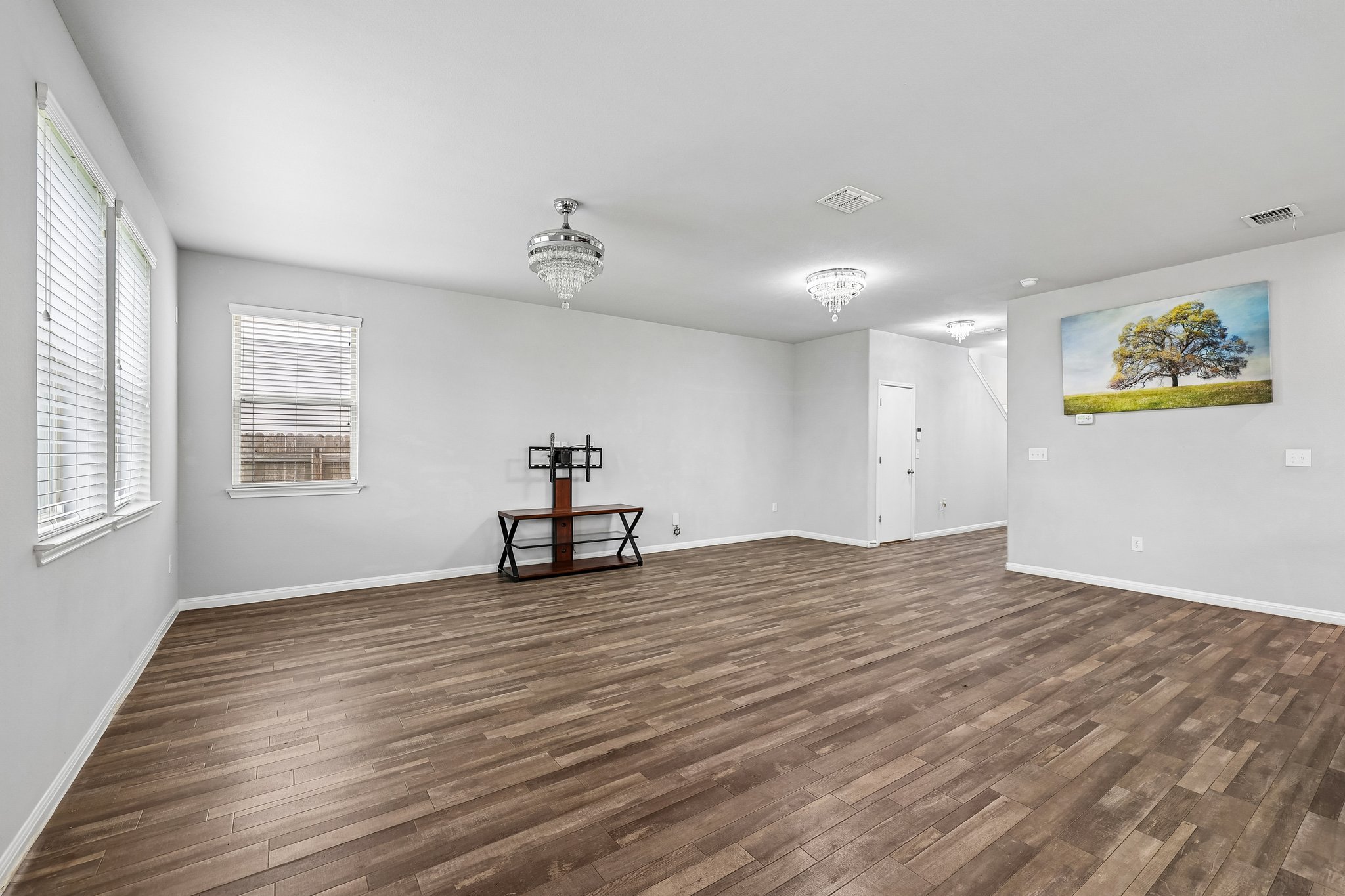 387 Guemal Road Buda, TX 78610 - Photo 4 of 39 Spacious living area featuring wood-finish flooring, light gray wall paint, and multiple windows with blinds