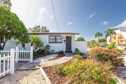 a yellow and red house with a flower garden in front of it