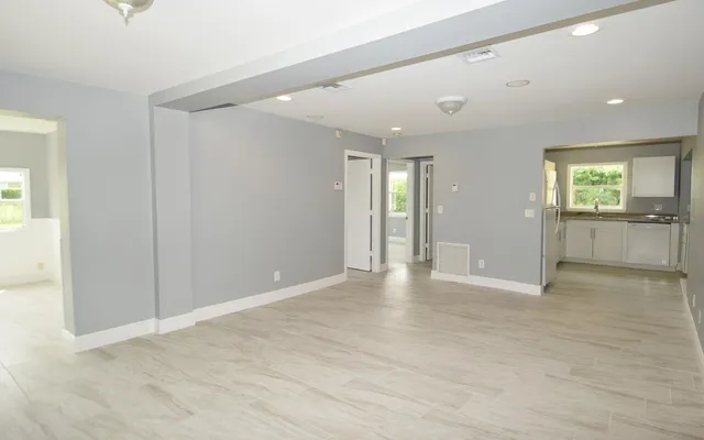 an empty room with kitchen view and windows