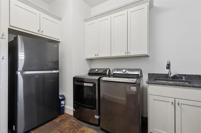 a kitchen with stainless steel appliances granite countertop a refrigerator a stove a sink and white cabinets