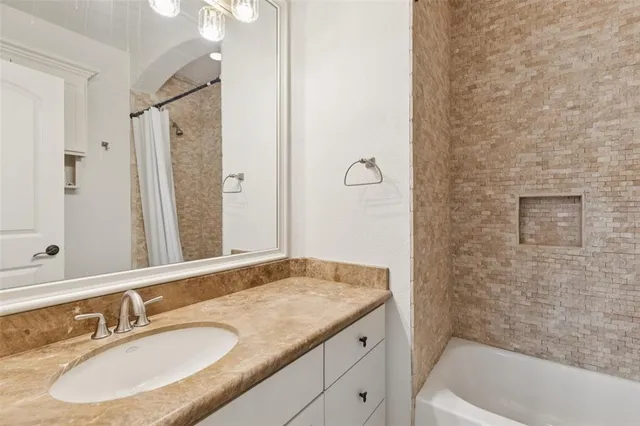 a bathroom with a granite countertop sink a mirror and a bathtub
