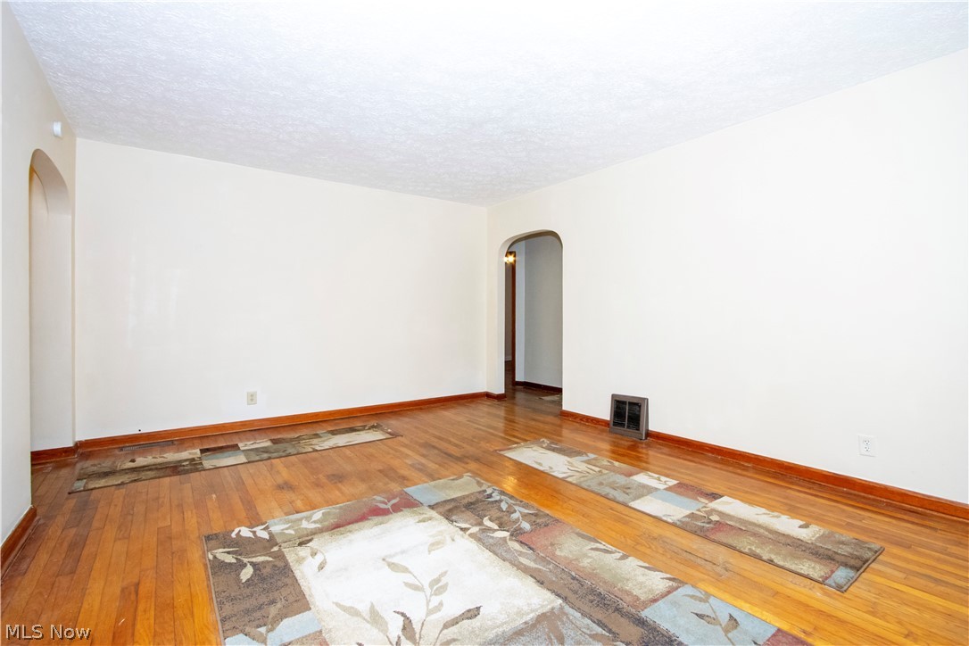 310 North Seneca Street Rittman, OH 44270 - Photo 9 of 28 Unfurnished room with arched walkways, hardwood / wood-style floors, and a textured ceiling
