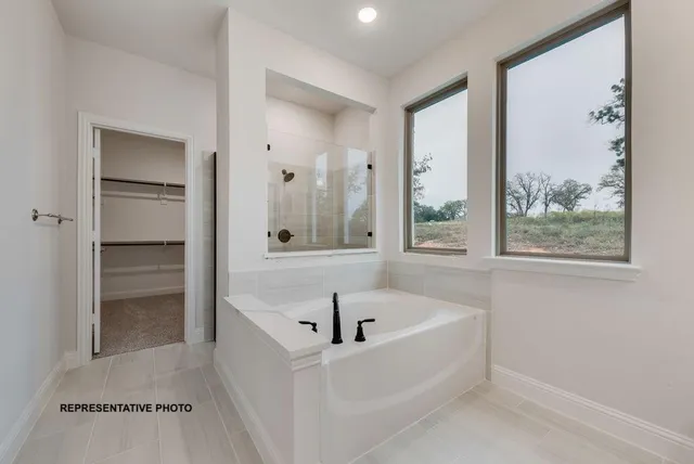 a white bath tub sitting in a en suite bathroom next to a window
