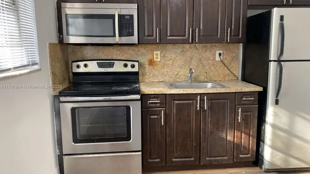 a kitchen with stainless steel appliances granite countertop a stove microwave and refrigerator