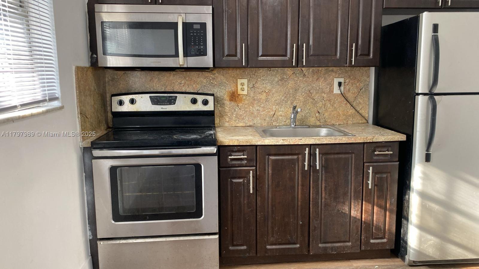 1173 Northwest 65th Street Miami, FL 33150 - Photo 5 of 7 a kitchen with stainless steel appliances granite countertop a stove microwave and refrigerator