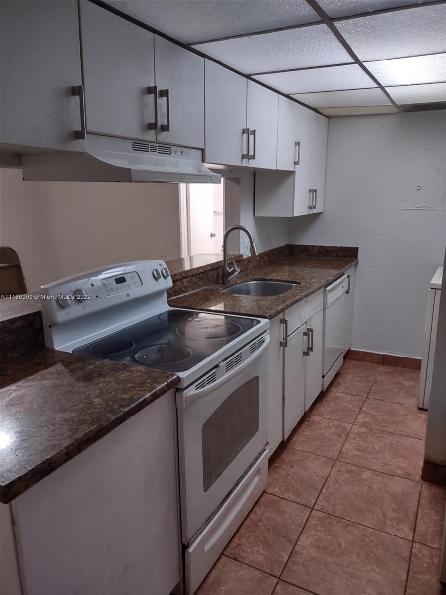 4445 Treehouse Lane, Unit A Tamarac, FL 33319 - Photo 3 of 16 a kitchen with granite countertop a stove sink and cabinets