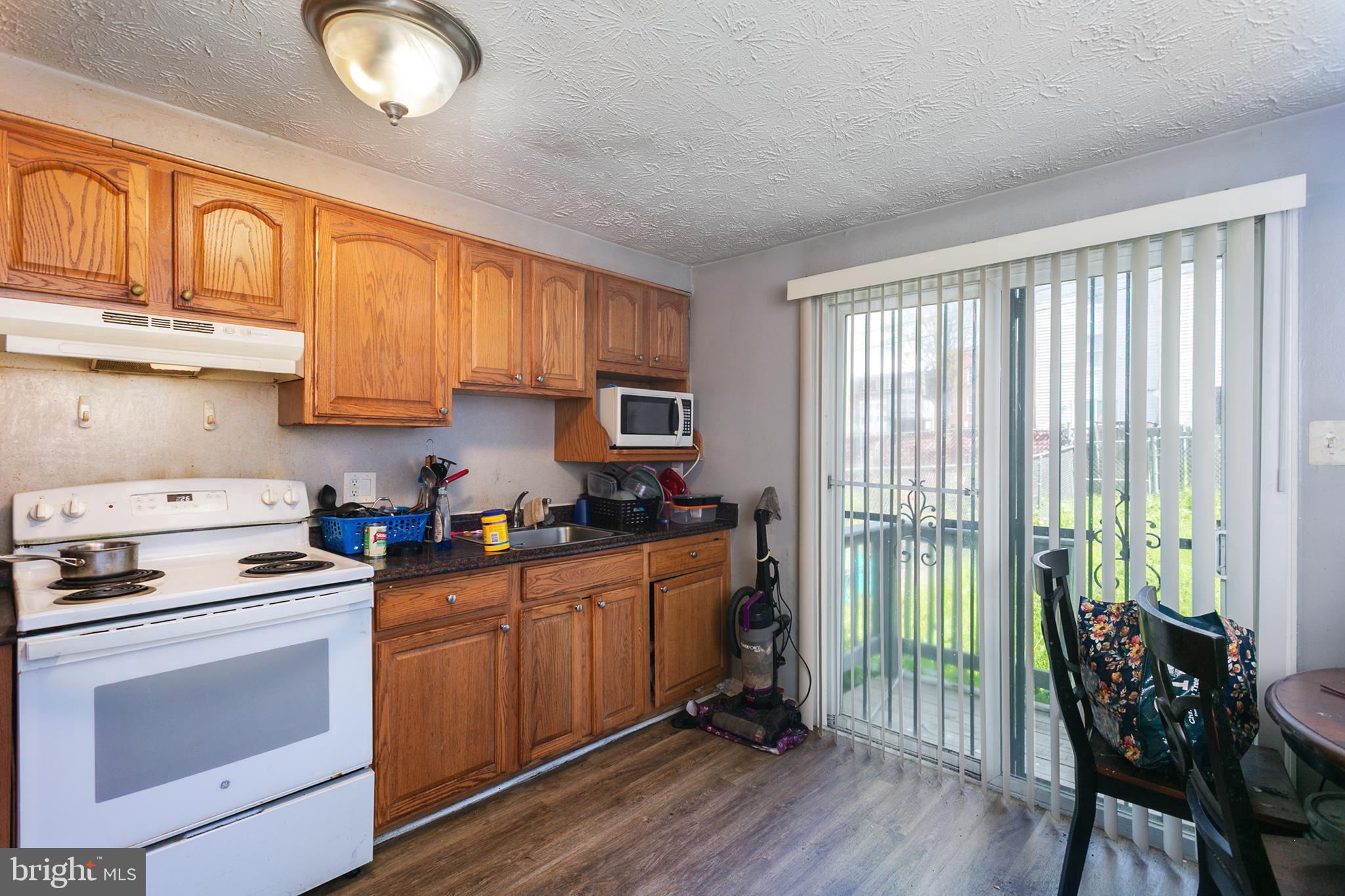 1217 Division Street Baltimore, MD 21217 - Photo 2 of 14 a kitchen with stainless steel appliances granite countertop a stove a sink and white cabinets with wooden floors
