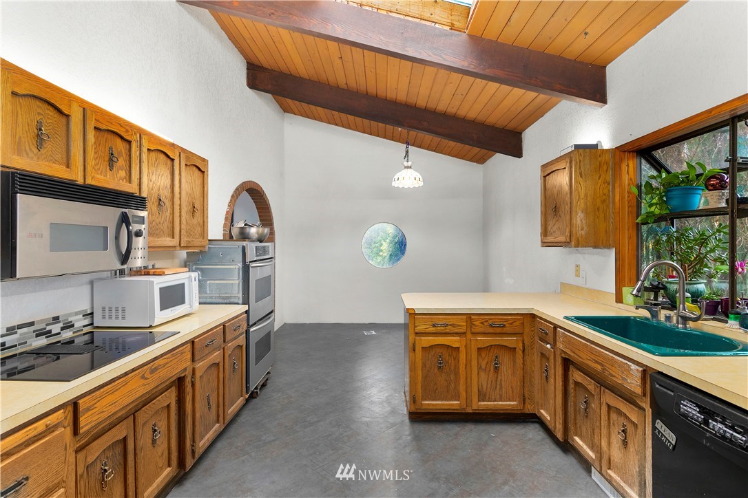 10316 Vernon Road Lake Stevens, WA 98258 - Photo 6 of 25 a kitchen with stainless steel appliances granite countertop a sink a stove top oven a chimney wooden cabinets and floors
