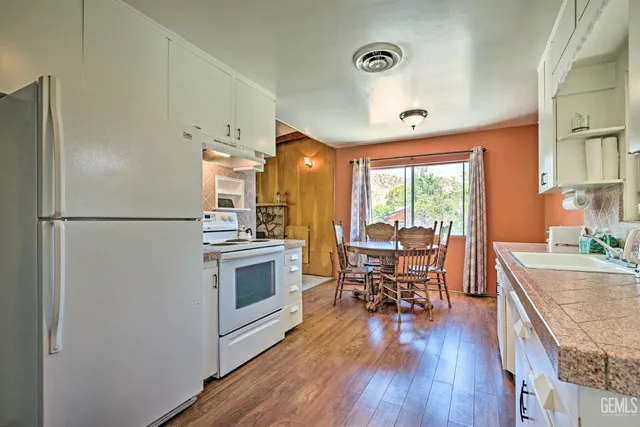 a kitchen with stainless steel appliances a refrigerator a sink dishwasher a stove and a dining table with wooden floor