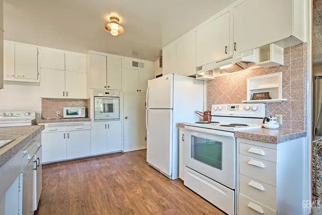a kitchen with granite countertop a refrigerator stove and white cabinets