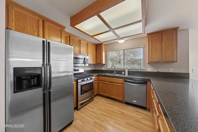 a kitchen with stainless steel appliances granite countertop a sink a stove and a refrigerator