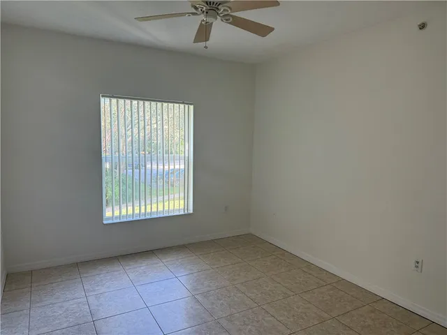 an empty room with a window and a fan