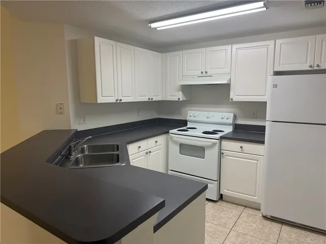 a kitchen with white cabinets sink and white appliances
