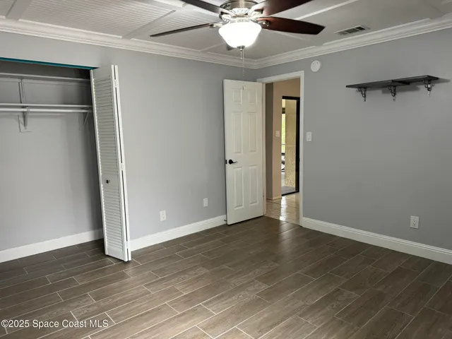 an empty room with wooden floor closet and windows