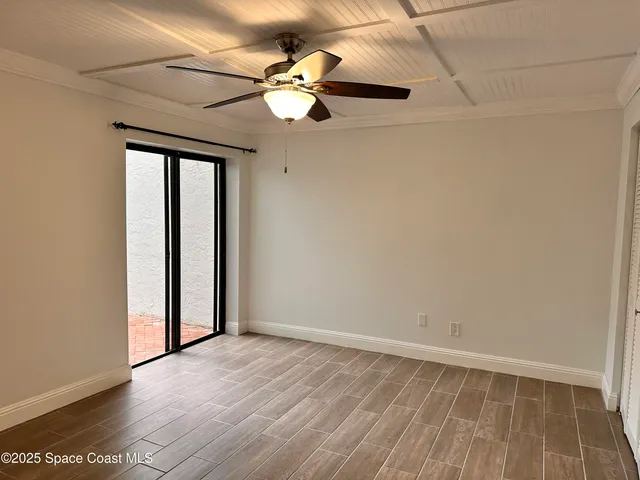 an empty room with wooden floor fan and windows