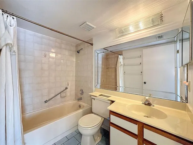 a bathroom with a granite countertop bathtub shower sink vanity and toilet
