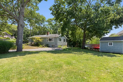 a view of a house with a yard and large trees