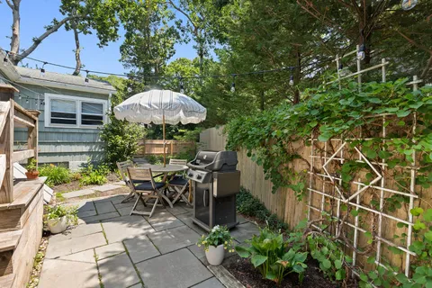 a view of a patio with table and chairs potted plants and a large tree