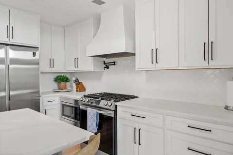 a kitchen with white cabinets and appliances