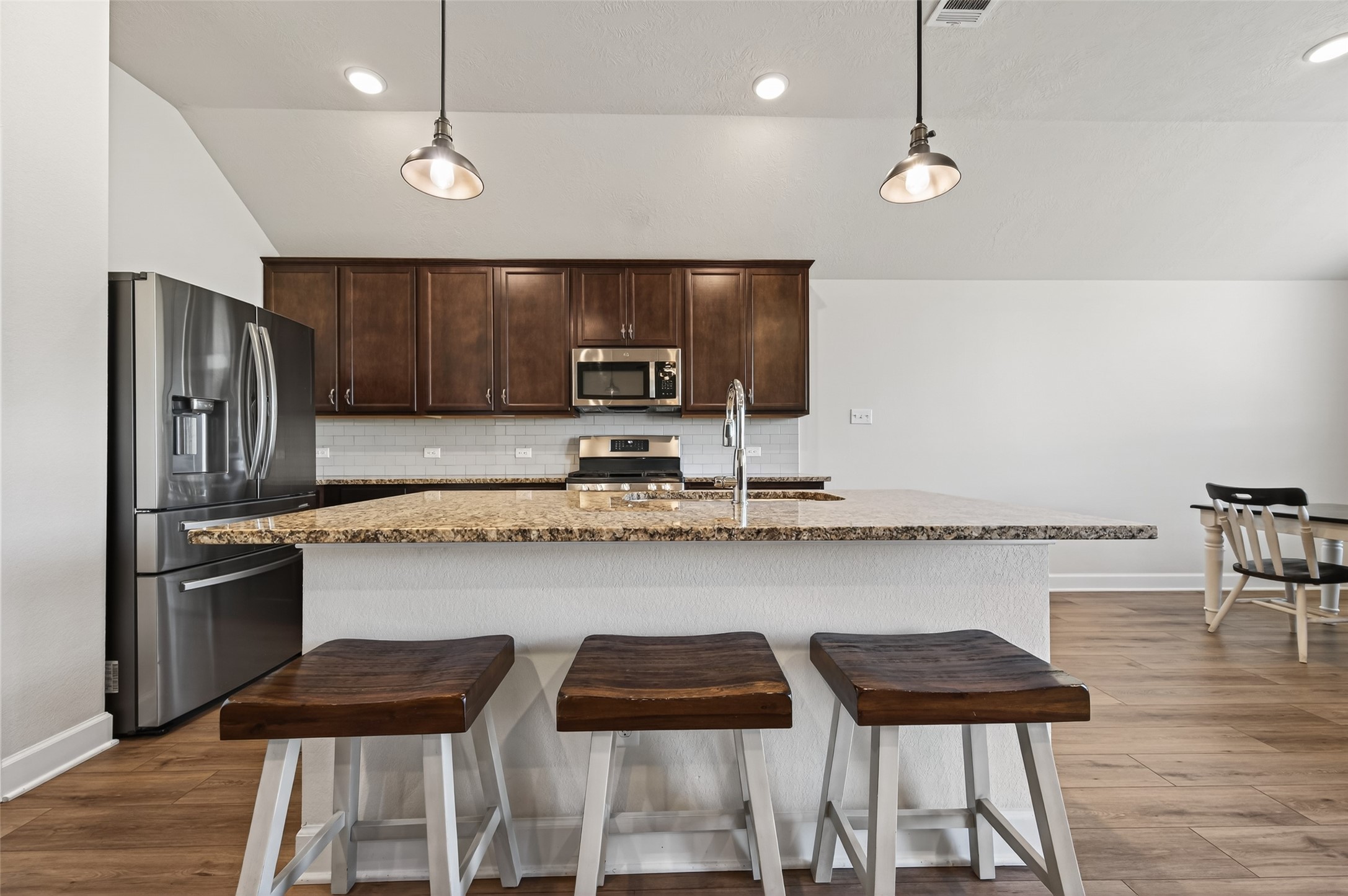 917 Farm Path Brenham, TX 77833 - Photo 12 of 43 a kitchen with stainless steel appliances granite countertop a stove top oven a sink a dining table and chairs
