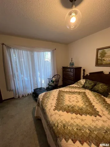 a bedroom with a bed and dresser with wooden floor