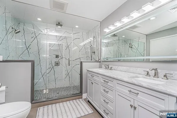 a bathroom with a shower sink vanity mirror and toilet