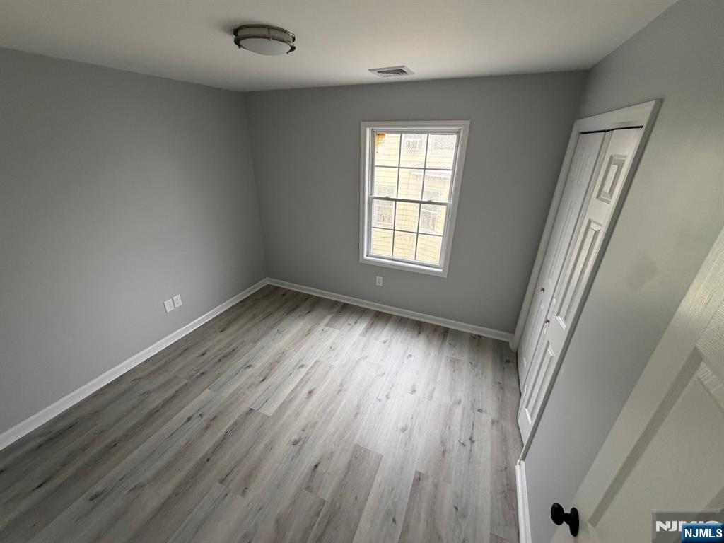 329 Fair Street, Unit 329 Paterson, NJ 07501 - Photo 11 of 14 an empty room with wooden floor and windows