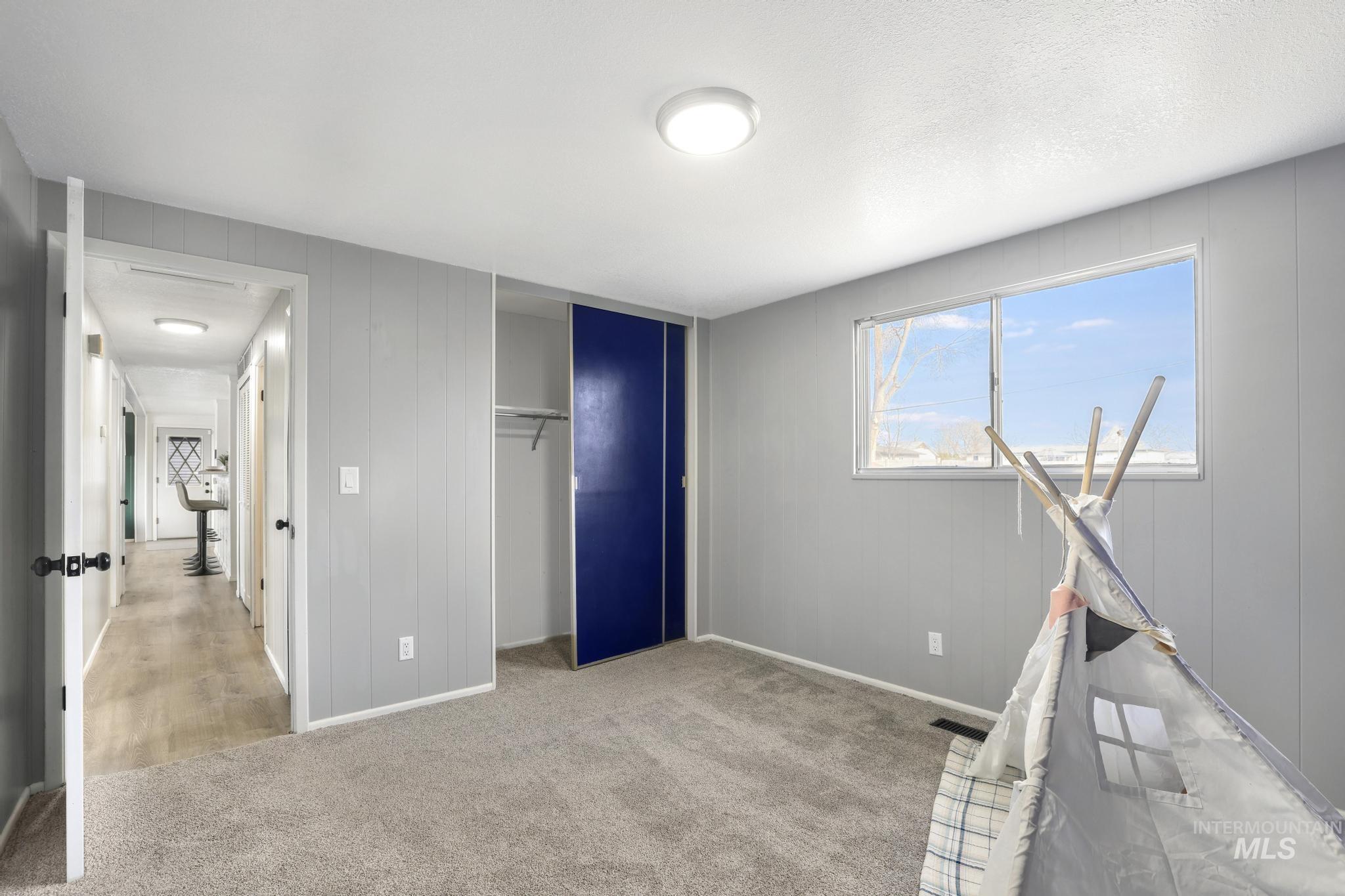 1840 V Street Heyburn, ID 83336 - Photo 15 of 45 Unfurnished bedroom with a closet, light carpet, and wood walls